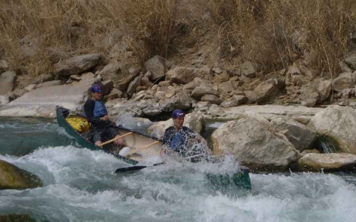 two gap year students paddle a canoe through whitewater on an outward bound expedition in texas